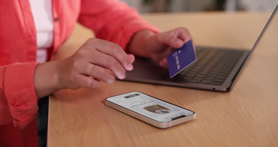Woman with credit card using smartphone for shopping online at wooden table indoors, closeup