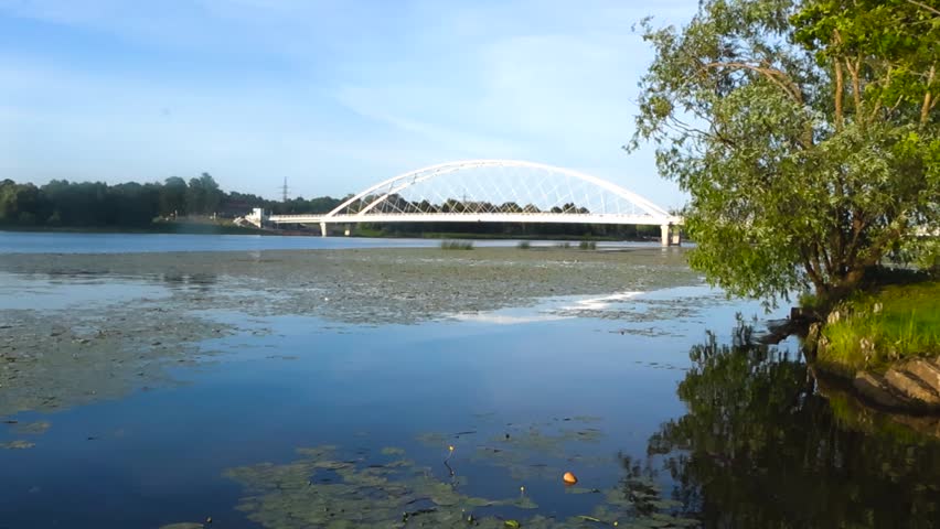 Picturesque view of the white arched Raama bridge spanning across the calm Parnu river