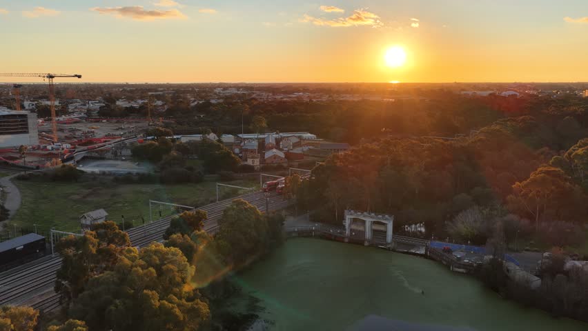 Adelaide CBD, South Australia, 9 Jul 2026 – 4K aerial drone footage of railway corridor, commuter trains, modern skyline, office towers and golden sunset cityscape