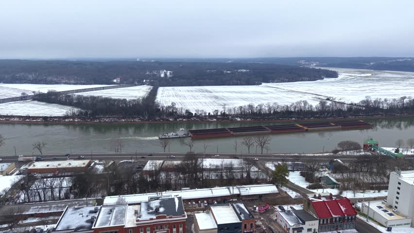 Aerial drone shot of a barge travelling down the Cumberland River in Clarksville Tennessee after a snowstorm