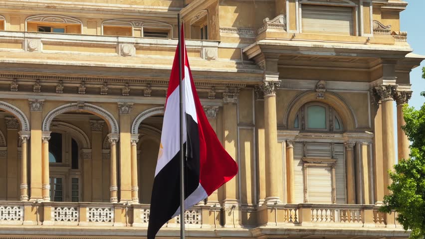 Egyptian National Flag waving near Neoclassical Historic Building Facade in Downtown Cairo