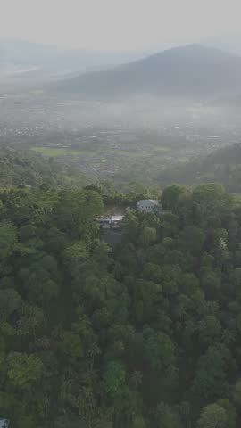 Aerial Drone View of Tropical Forest, Coastal Hills and Scenic Ocean Landscape. 
Cinematic aerial drone footage showing lush tropical forest and green coastal hills surrounding houses, gradually revealing a beautiful ocean landscape with small islands in the distance. Peaceful natural scenery, tropical coastline, and expansive mountain and sea views. Ideal for travel, tourism, nature, environmental, resort, tropical destination, and landscape projects.