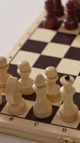 Close-up of a hand moving a white knight piece on a wooden chessboard, executing a strategic opening move in a classic intellectual board game against the black opponent