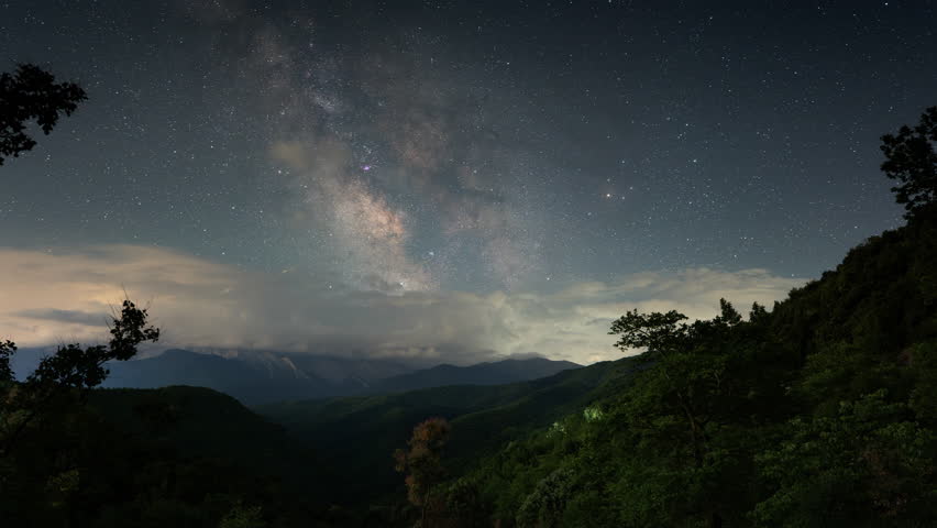Milky Way core arches above the dark slopes of Mount Olympus in Greece as clouds drift in this night sky timelapse.