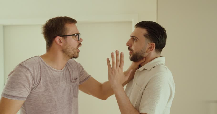 An aggressive man grabs another man by the neck during a heated confrontation. Concept of conflict, intimidation, aggression, domestic dispute, and violence.