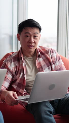 A woman and a man of diverse ethnicities collaborate on laptops while seated comfortably in a modern office setting