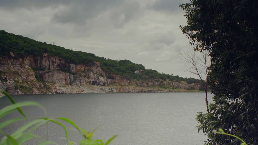 Scenic Quarry Lake Surrounded by Rocky Hills Landscape in Overcast
