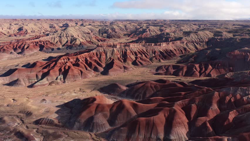 Aerial view of the colorful rock formations and rugged terrain of the Painted Badlands under a clear sky in Winslow, Arizona, United States.