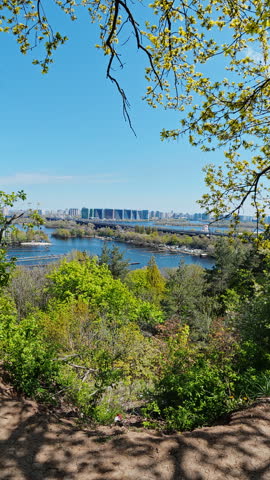 Scenic panoramic view of Kyiv city skyline with Dnieper river and lush green spring forest under clear blue sky. Beautiful urban nature landscape in Ukraine