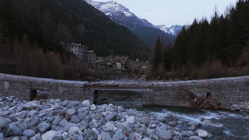 Push forward through a breathtaking mountain valley, revealing a scenic alpine village and its pristine river.