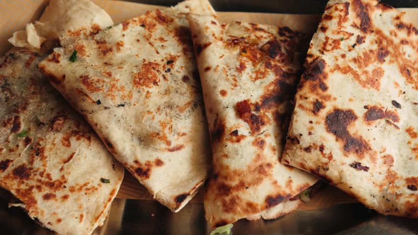 Close-up of a freshly cooked cheese quesadilla with a crispy golden tortilla. Traditional Mexican dish served hot in a restaurant, showing melted filling and toasted texture. High quality 4k footage
