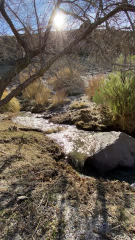 Mountain stream flowing through a rugged landscape, captured in a casual cellphone video showing clear running water and natural surroundings.