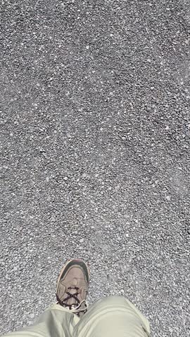 First-person view walking across rocky terrain before turning toward a frozen lake, captured in an anonymous cellphone-recorded outdoor clip.