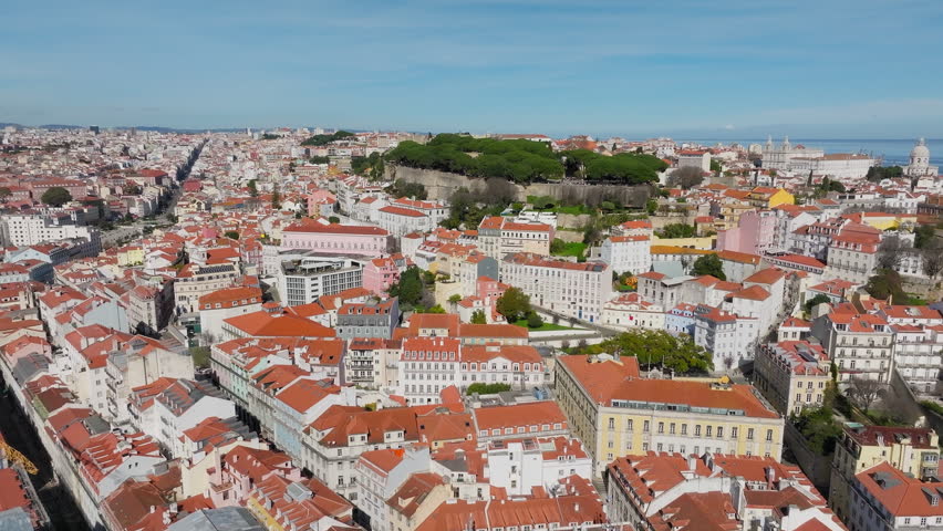 Castelo de Sao Jorge hilltop moorish castle and royal residence with palace ruins, archaeological museum surrounding neighbourhoods of Castelo, Mouraria, and Alfama, Lisbon, Drone shot
