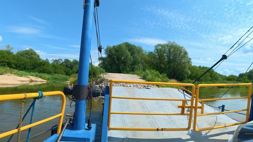 Ferry approaching riverbank on rural river crossing.