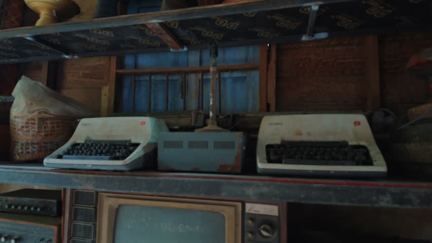Vintage typewriters, retro television and antique electronics displayed on rustic wooden shelves, Nostalgic museum interior with collectible analog technology and historical artifacts 4k
