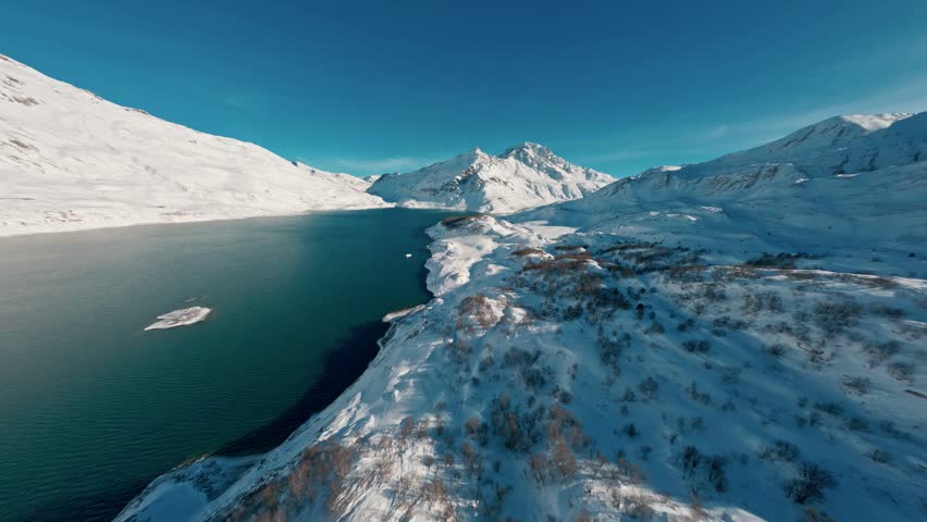 A stunning deep blue reservoir nestled among snow-covered mountain ridges.