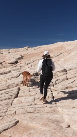 Vertical View of Young Woman With Dog Hiking on Rocky Hill in Desert Wilderness of Utah USA