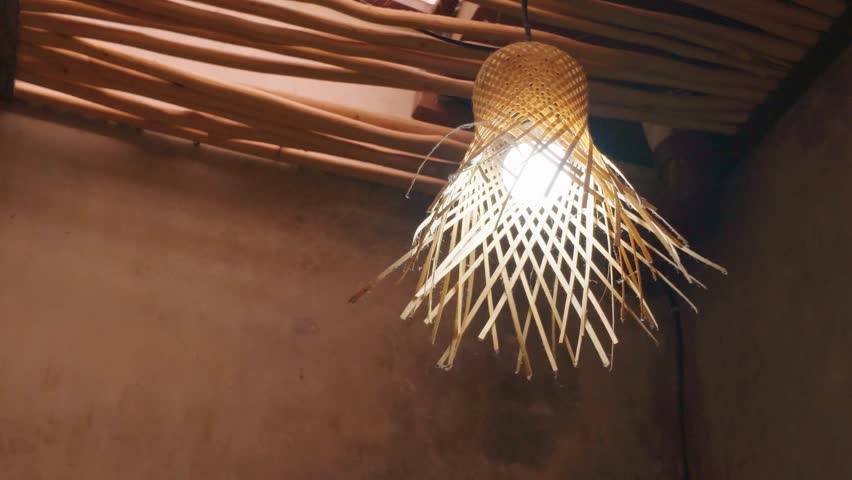 Unique woven bamboo ceiling lamp hanging from a rustic wooden ceiling.