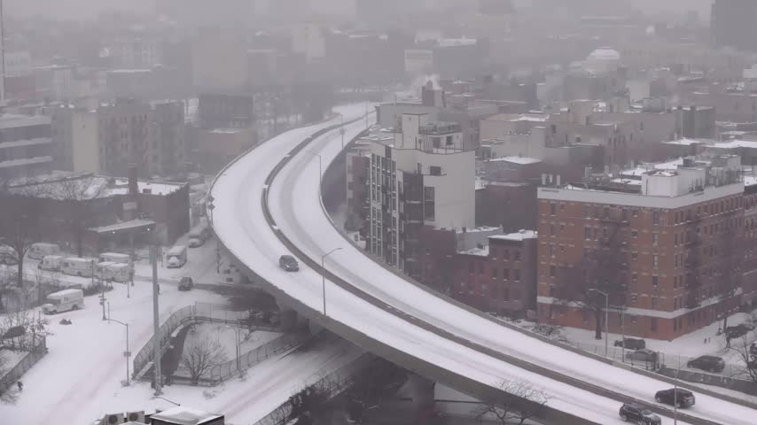 Aerial of snow covered elevated highway curving above Brooklyn rooftops