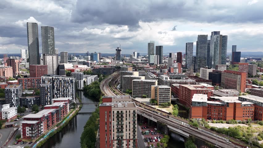 High-angle view of Manchester’s urban landscape featuring residential towers and canals under a cloudy sky.