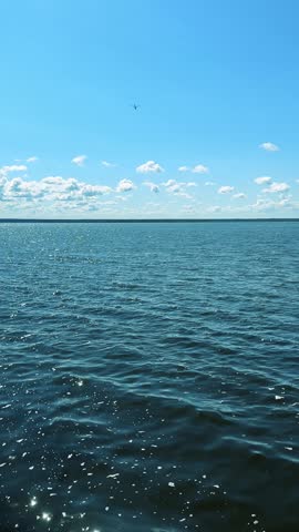 A Serene View of a Tranquil Lake with Sparkling Water Under a Clear Sky and Lush Cloud Patterns, Featuring a Wooden Dock Extending into the Calm Waters