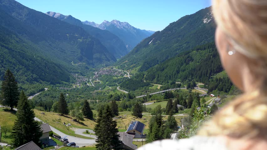 A view over the shoulder of a girl looking at a city in a mountain valley