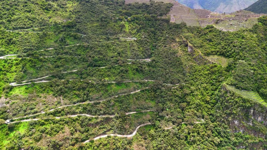 Aerial view of the winding mountain road and serpentine curves leading to the ancient Incan citadel of Machu Picchu in Peru.