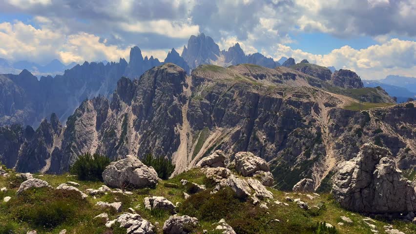 serene rocky mountain landscape with green vegetation under a partly cloudy sky, aerial view of majestic terrain, travel and adventure background, nature and landscapes, clean and detailed.