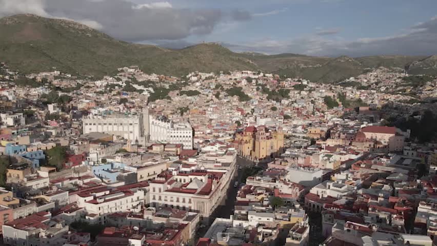 Panoramic aerial view of Guanajuato city center with the university and basilica surrounded by colorful hills in Mexico