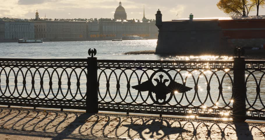 Isaac cathedral, Winter Palace, picturesque metal railings with a double-headed eagle and the crown of the Russian Empire on embankment in St. Petersburg, autumn sunset, incredible sun glare, Russia