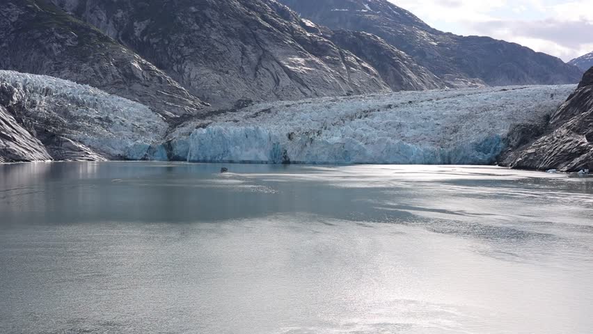 Alaska glacier with small touristic boat approaching it