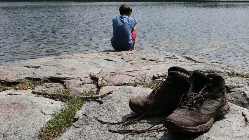 Teen hiker relaxing at the edge of a secluded mountain pond.  Cole pond, Enfield, New Hampshire.