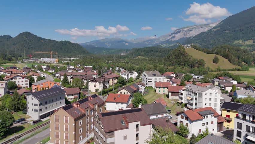 Aerial view of the village of Bonaduz in Graubünden, Switzerland with green fields and mountains in the background.