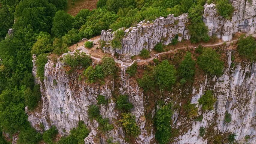 Aerial view from a high mountain viewpoint over the deep limestone cliffs and winding canyon floor of Vikos Gorge, Greece