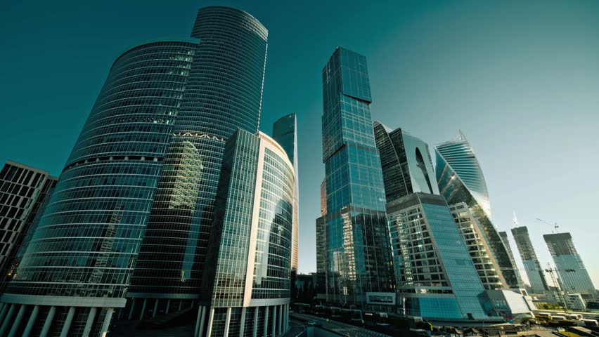 Panoramic view of Moscow showing a wide cityscape, busy streets, tall buildings, and urban architecture. The elevated view captures the scale of the Russian capital with a clear skyline and modern city surroundings.
