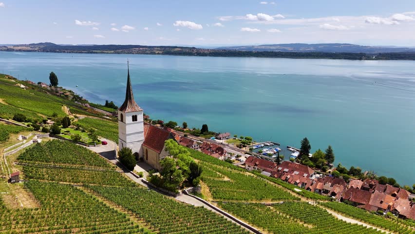 Ligerz, Lake Biel, Bern, Switzerland, revealing St. Peter Church, terraced vineyards, the lakeside village and turquoise freshwater during a smooth drone pullback.