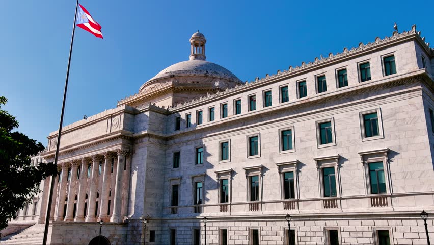 4K tilt up drone shot revealing the Capitolio de Puerto Rico building in San Juan, Puerto Rico. Shows the Puerto Rican flag and historic dome facade. For tourism, government, culture.