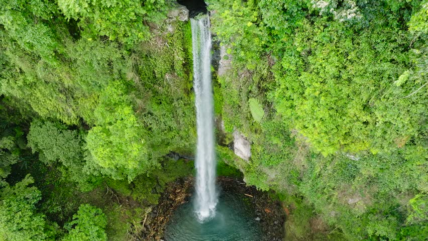 Waterfall with green water surrounded by forest in Camiguin Island. Katibawasan Falls. Philippines.