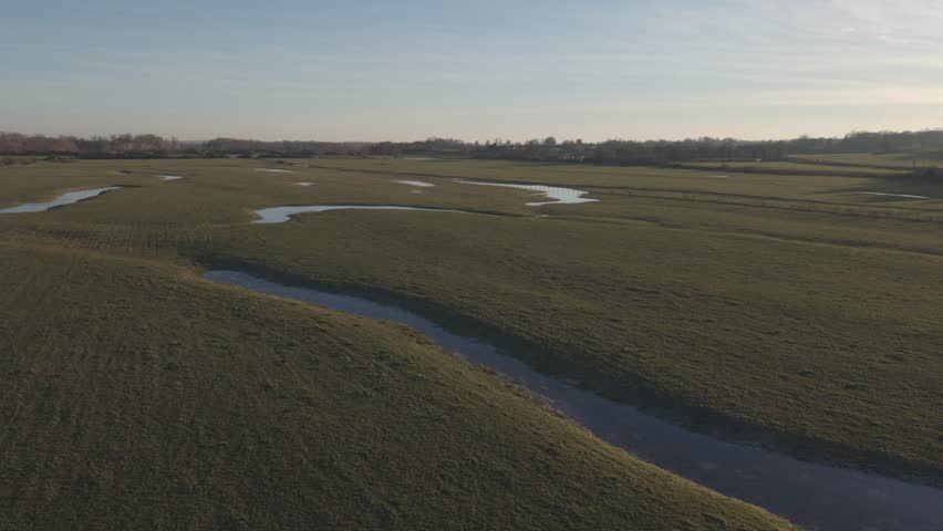 An aerial view shows open wetland fields with winding water channels in the Loire Valley at dusk.
