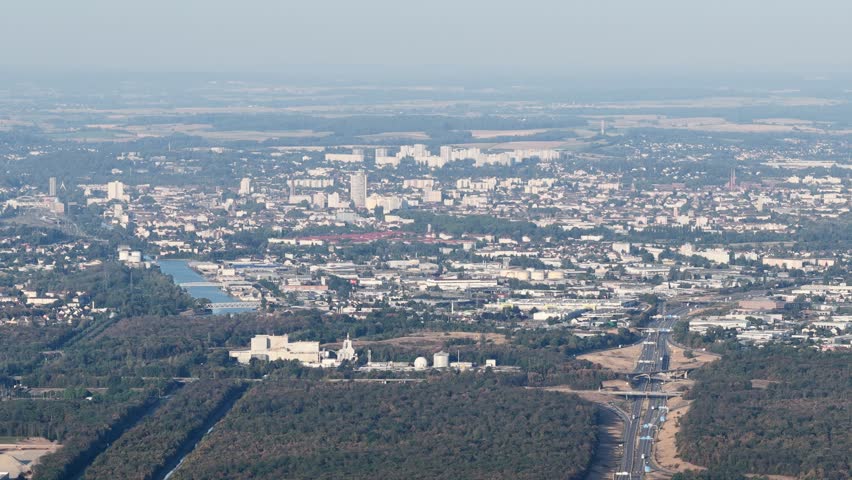 Aerial view of the industrial landscape and surrounding forest near the highway in Bantzenheim, Grand Est, France.