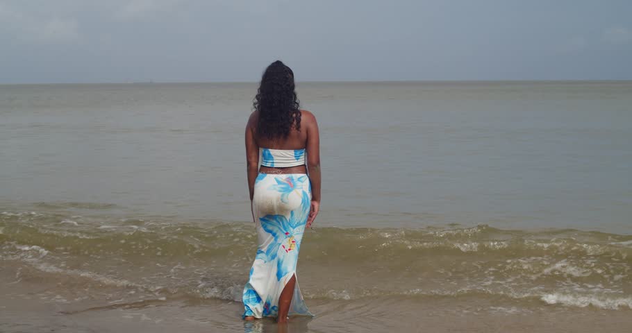 Relaxing Moment: Woman in Blue and White Sundress Sitting on Shore