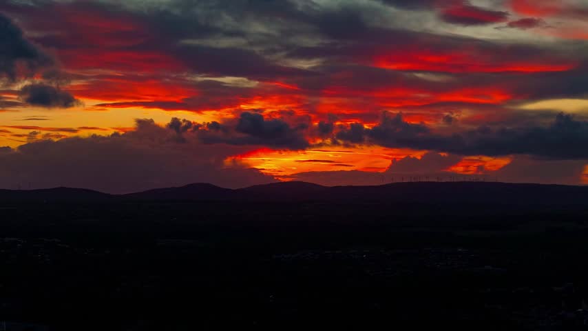 Cinematic timelapse of a dramatic fiery sunset sky with colourful clouds above distant rolling hills in Florida, creating an atmospheric evening landscape