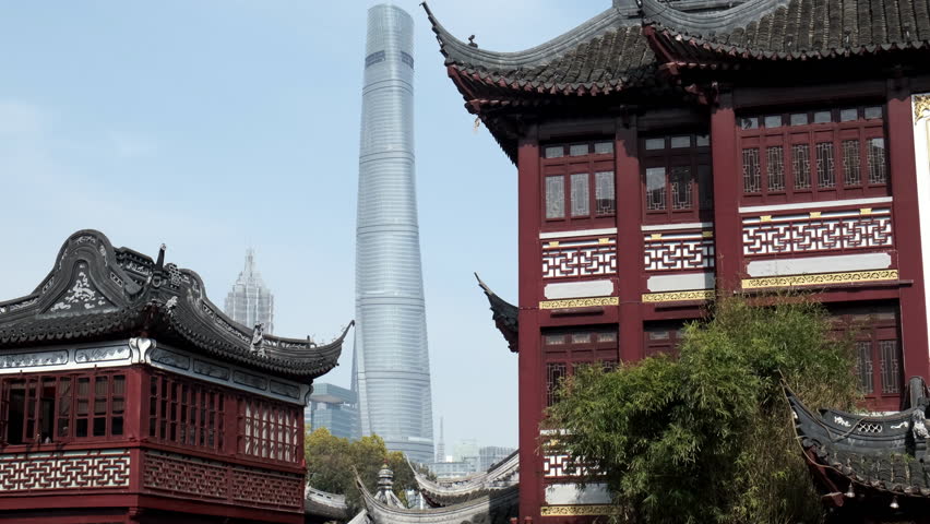 The iconic Shanghai Tower stands in the distance framed by traditional Chinese architecture with ornate tiled roofs in Shanghai.