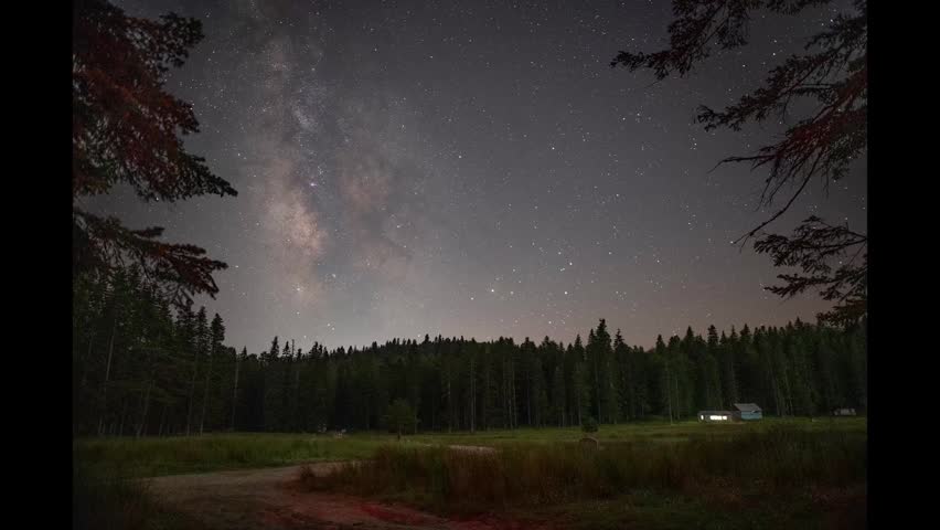 Stunning night scene showcasing the Milky Way galaxy above a tranquil forest and mountain range.