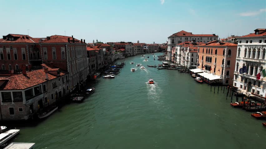 High-angle shot showing boats and water taxis navigating the Grand Canal in Venice, Italy, surrounded by historic Venetian buildings.
