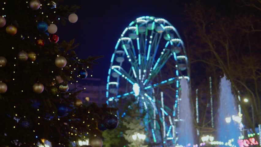 A Christmas market lights up the night with colorful decorations and a large ferris wheel. Visitors enjoy the festive atmosphere, shopping, and holiday treats.