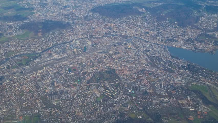 High-altitude aerial view from a passenger plane over Zurich, Switzerland, showcasing Lake Zurich, residential neighborhoods and commercial districts shortly after departure from Kloten airport