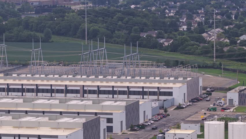 White data center campus building with power lines and huge structure holding data, artificial intelligence, and online tech storage near Columbus, OH suburban city of Hilliard, Ohio from drone aerial