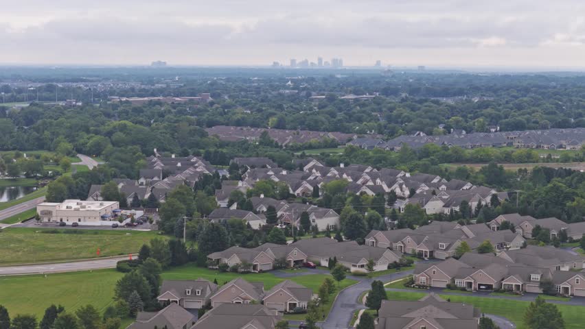 Drone aerial above city of Hilliard, Ohio suburban landscape as a suburb outside Columbus, OH with townhomes, residential units, duplex homes, houses, and rental buildings in middle class neighborhood